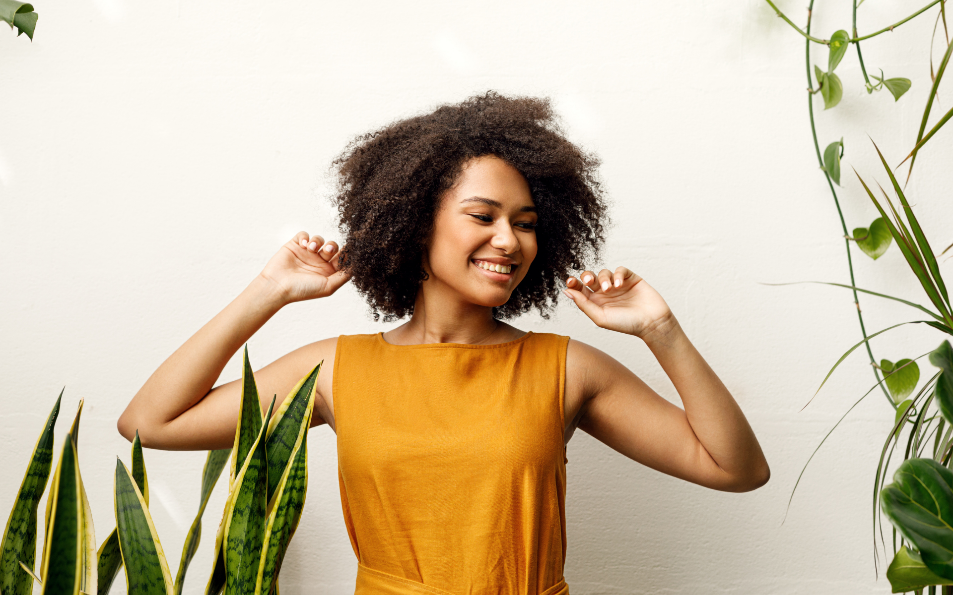 A black woman wearing an orange dress surrounded by plants